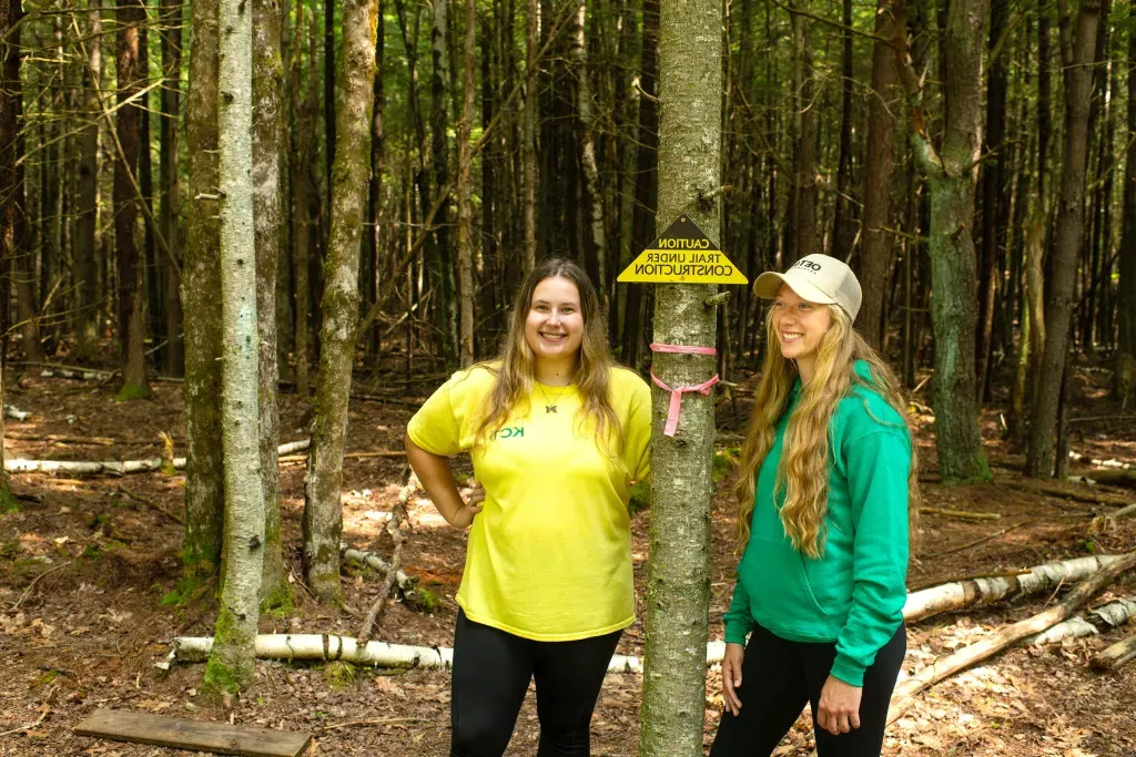 U N E students Julianne Lapiere and Mia Meister standing on a trail in Kennebunk