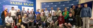 Members of UNE's Community pose in front of a mural inside the Alfond Forum